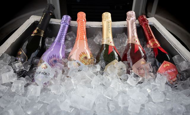 Vier Gläser Schaumwein nebeneinander auf einem hellen Tisch